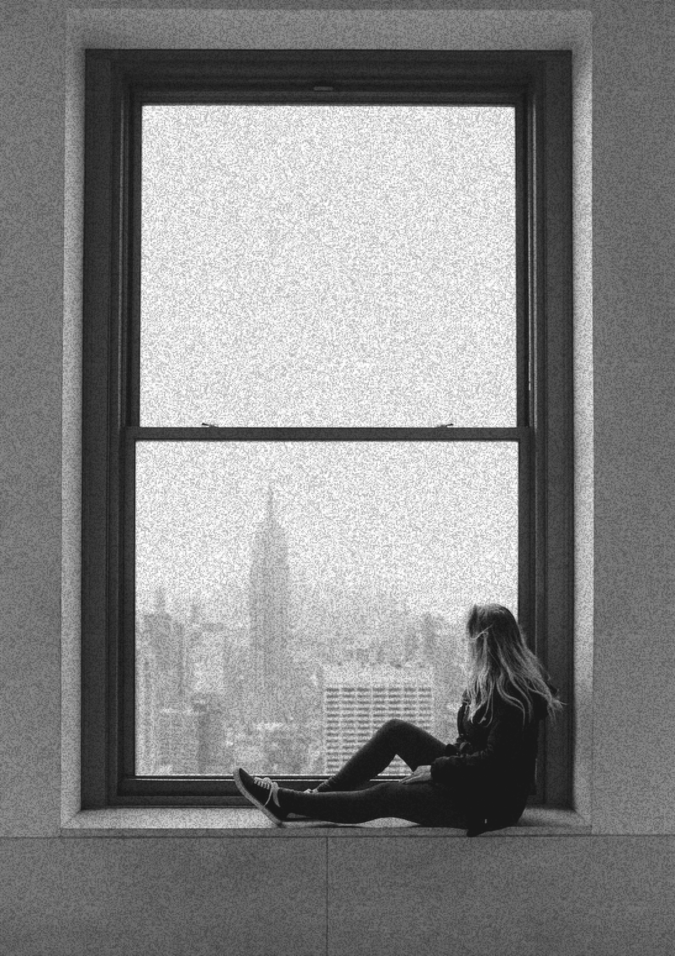 Uma mulher sentada no parapeito da janela olhando a cidade de Nova York.